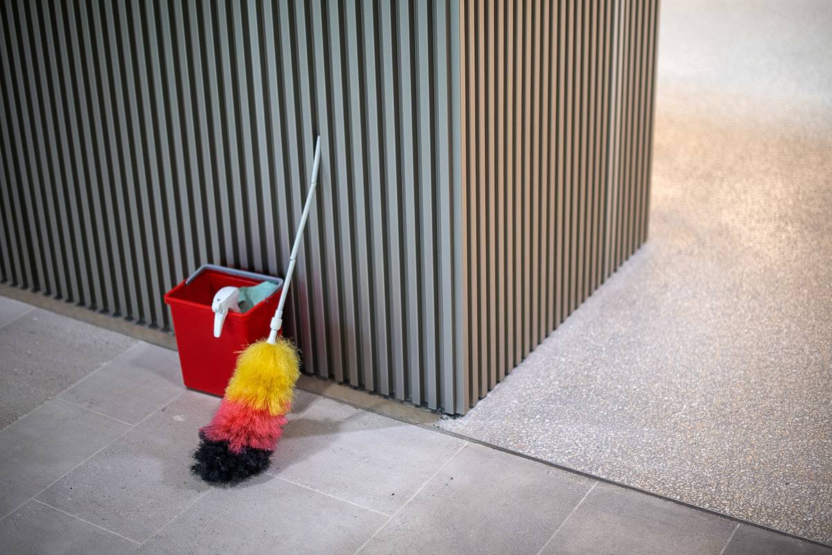 feather duster leaning against wall with cleaning products