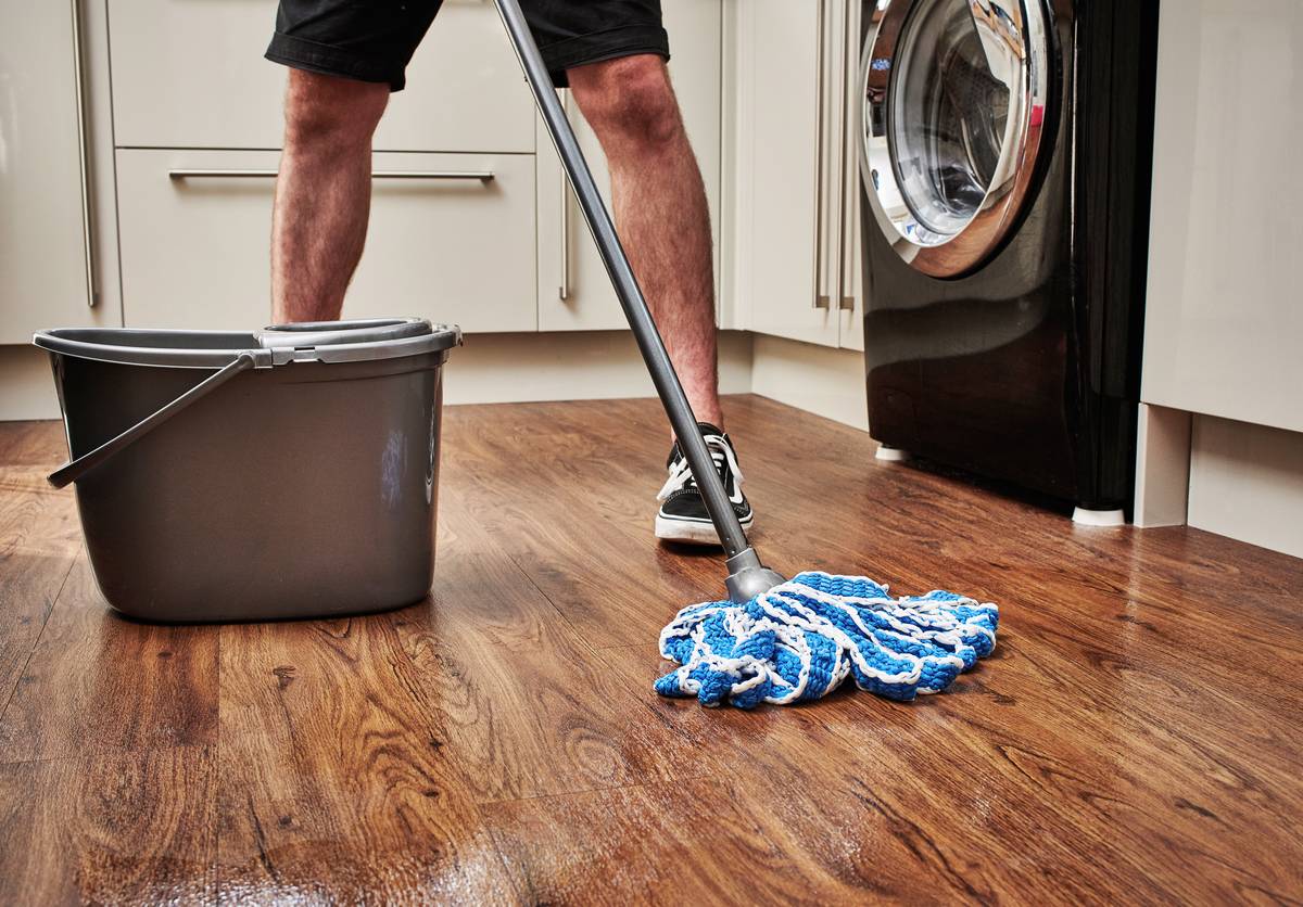 man cleaning wooden floor with mop and bucket