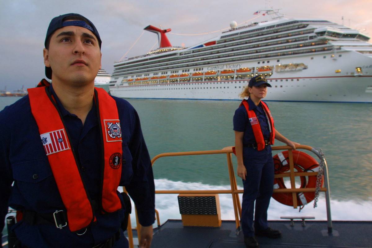 Coast guard members sail by a ship for security.